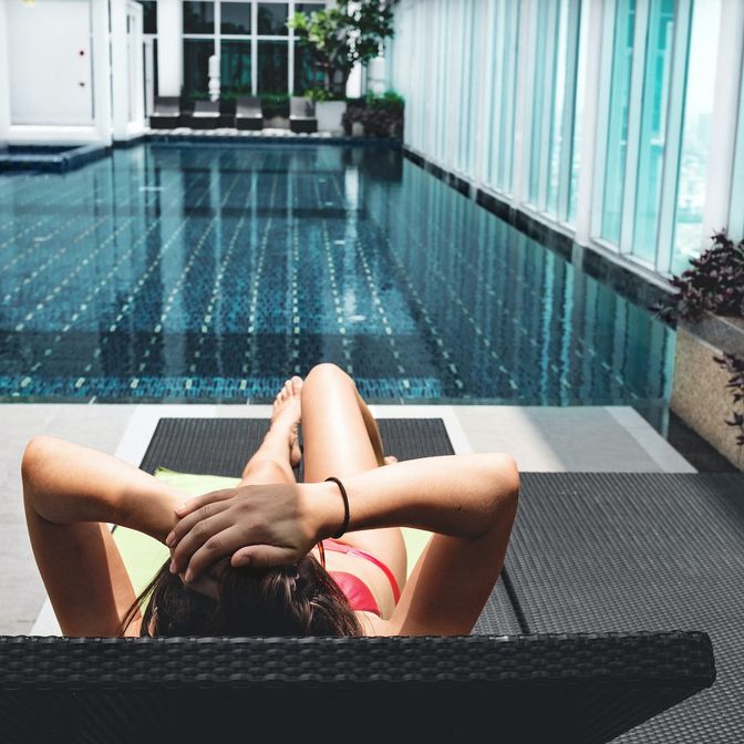 Person auf einer Liege an einem Hotel-Pool