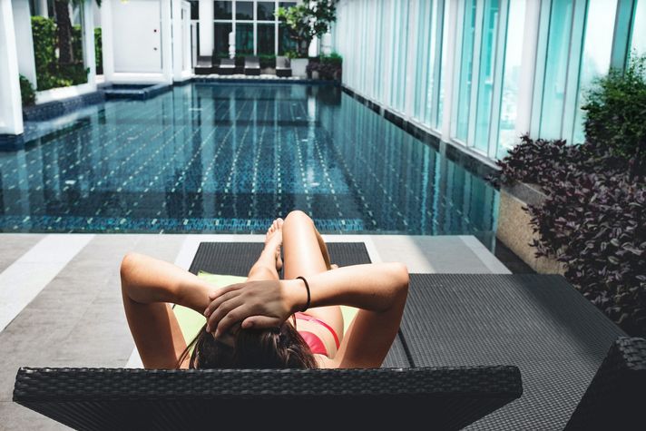 Person auf einer Liege an einem Hotel-Pool