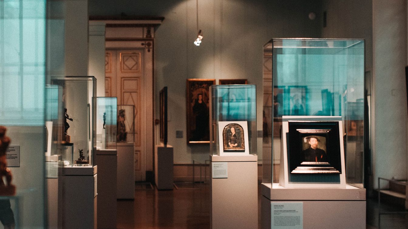 Raum in einem Museum mit mehreren Vitrinen und Gemälden