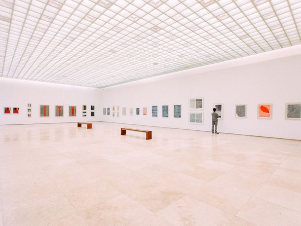 Großer, heller Raum in einem Museum mit zahlreichen Bildern an der Wand
