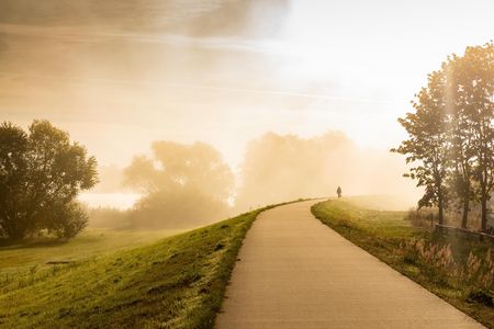 Wiesen und Deich mit Spazierweg bei Sonnenaufgang