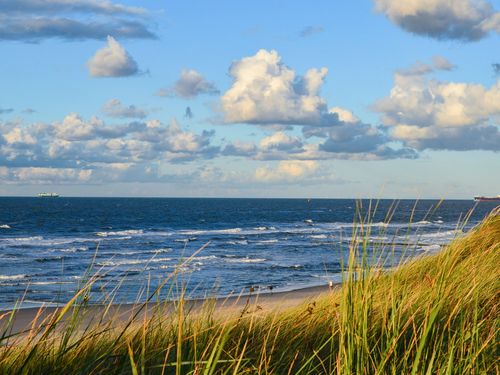 Dünen und Strand, dahinter Meer und bewölkter Himmel