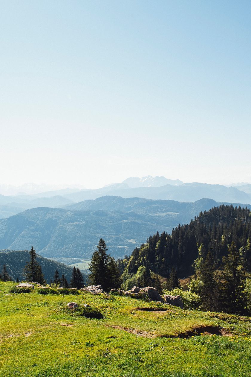 Bergpanorama mit grünen Wiesen im Vordergrund und blauem Himmel