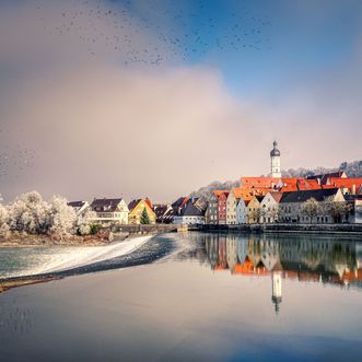 Kleine Stadt mit einem Kirchturm an einem See im Winter