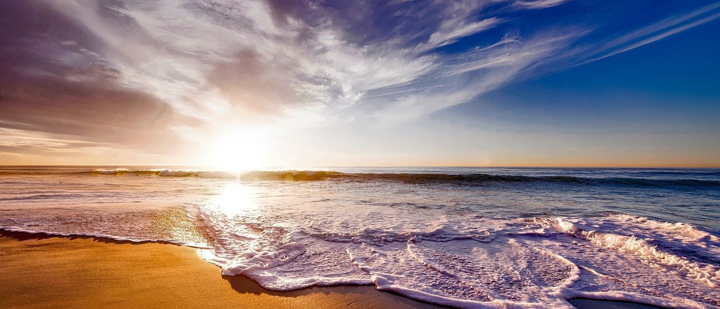 Sonnenuntergang am Meeresstrand Sonnenuntergang über dem Meer mit Wellen, die an einen sandigen Strand rollen.